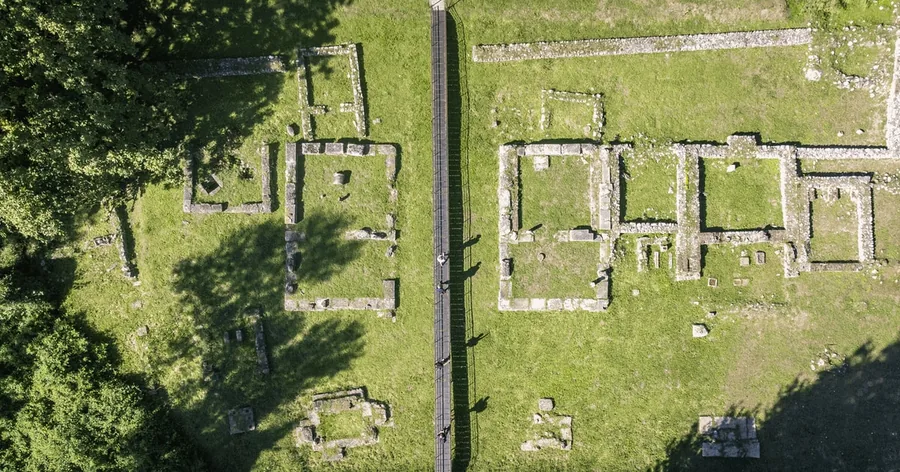 The stone foundations of ancient Dion seen from above among green grass