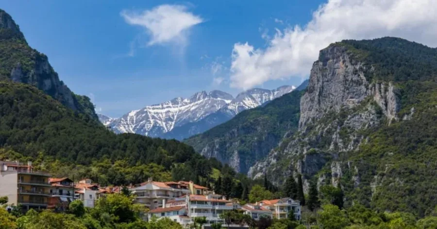 Litochoro's houses at the mouth of the forested gorge, snow on the high peaks behind